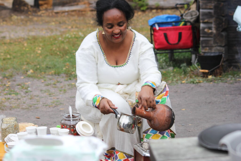 En kvinna lagar mat ut i vit klänning.