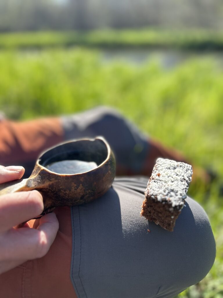 Bild på ben med en kakbit på knät och en kåsa kaffe.